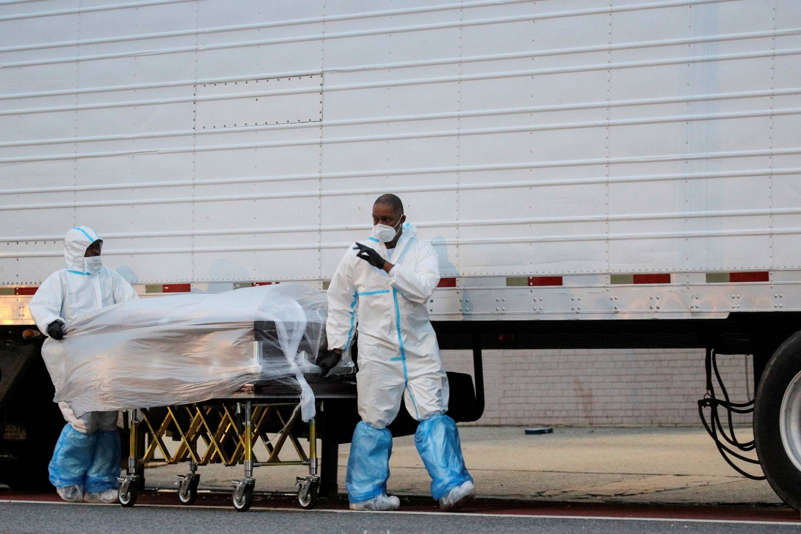 Workers roll a casket down a city street outside the Andrew T. Cleckley Funeral Services funeral home during the outbreak of the coronavirus disease (COVID-19) in Brooklyn, New York