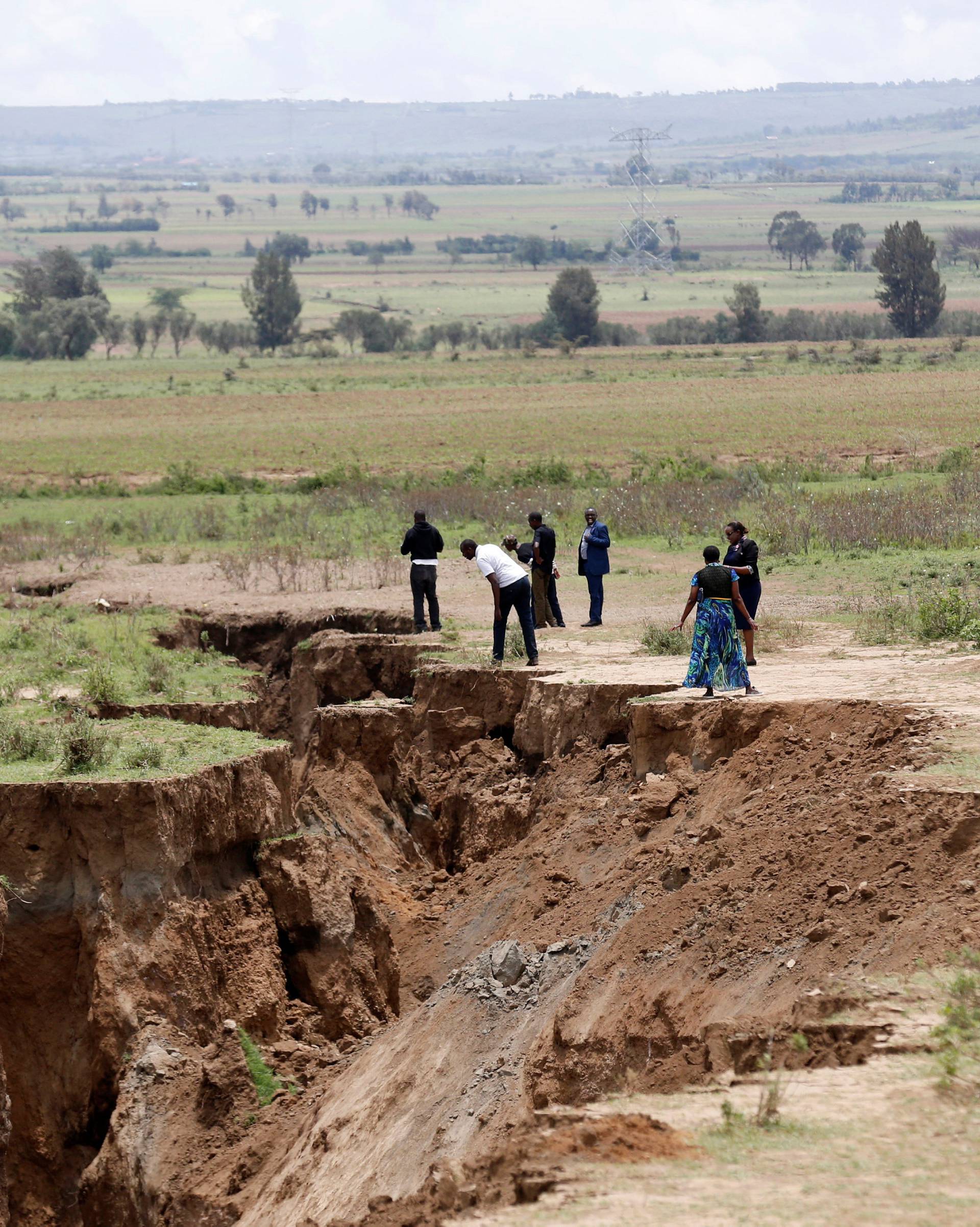 Residents look at a chasm suspected to have been caused by a heavy downpour along an underground fault-line near the Rift Valley town of Mai-Mahiu