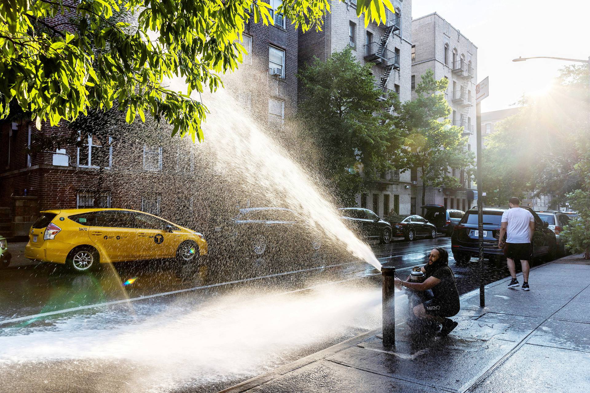 A man plays with an open hydrant during a hot and humid day in the Bronx borough of New York