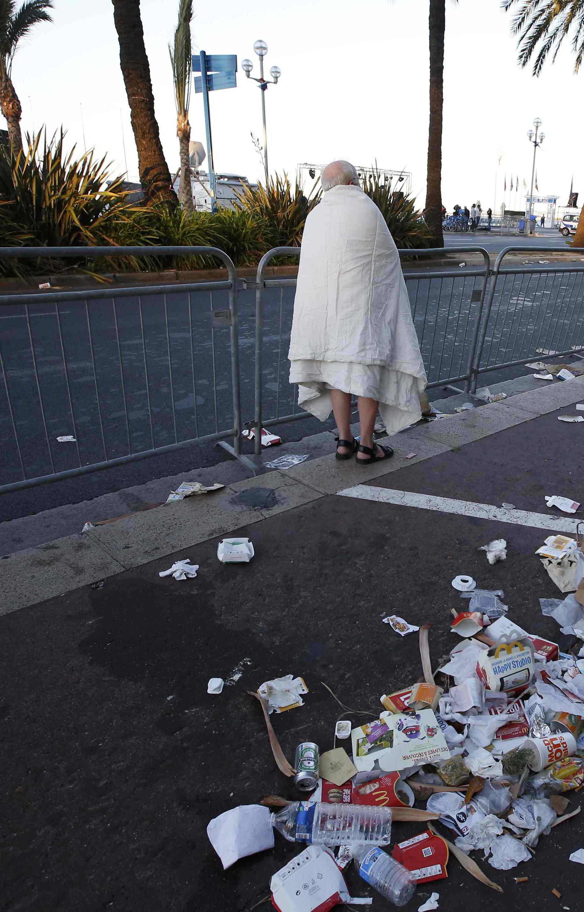 A man walks through debris on the street the day after a truck ran into a crowd at high speed killing scores celebrating the Bastille Day July 14 national holiday on the Promenade des Anglais in Nice