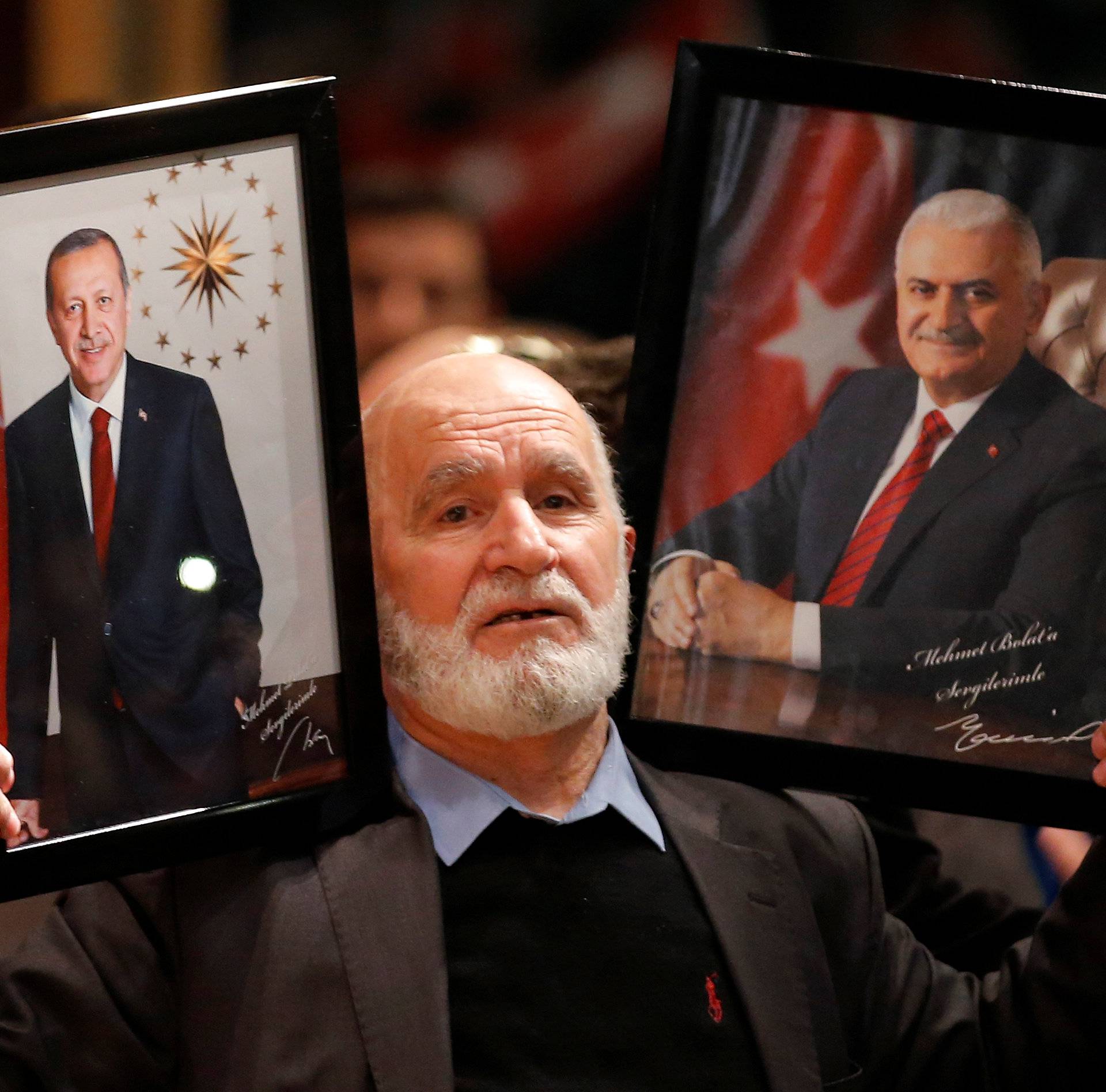 A supporter holds portraits of Turkish President Erdogan and Turkish Prime Minister Yildirim, ahead of the start of a political rally on Turkey's upcoming referendum, in Metz
