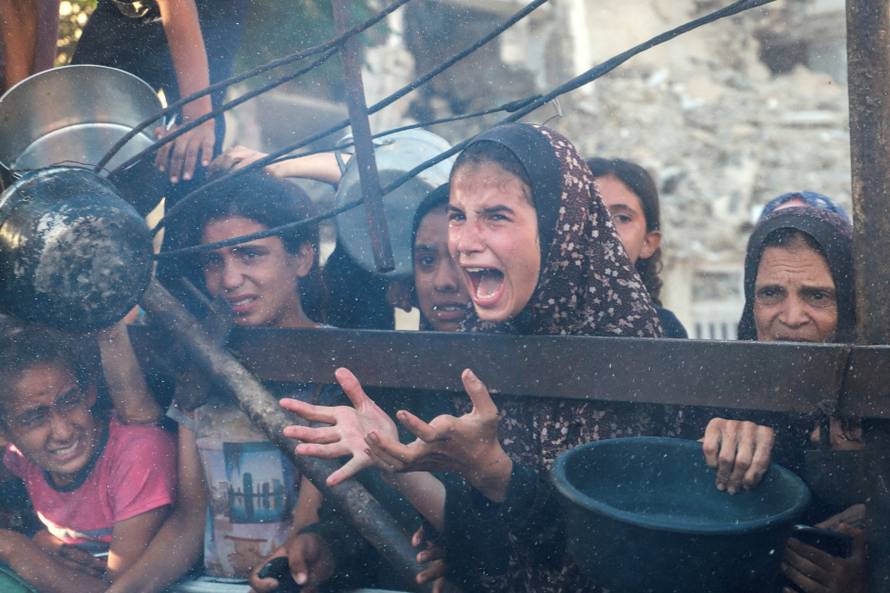 Palestinians wait to receive food from a charity kitchen amid hunger crisis, in Gaza City