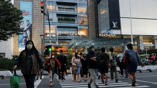 People cross a main road outside a shopping mall during afternoon rush hours in Jakarta