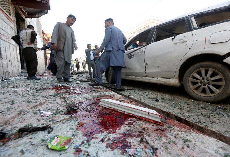 Afghan men inspect the site of a suicide bomb blast in Kabul