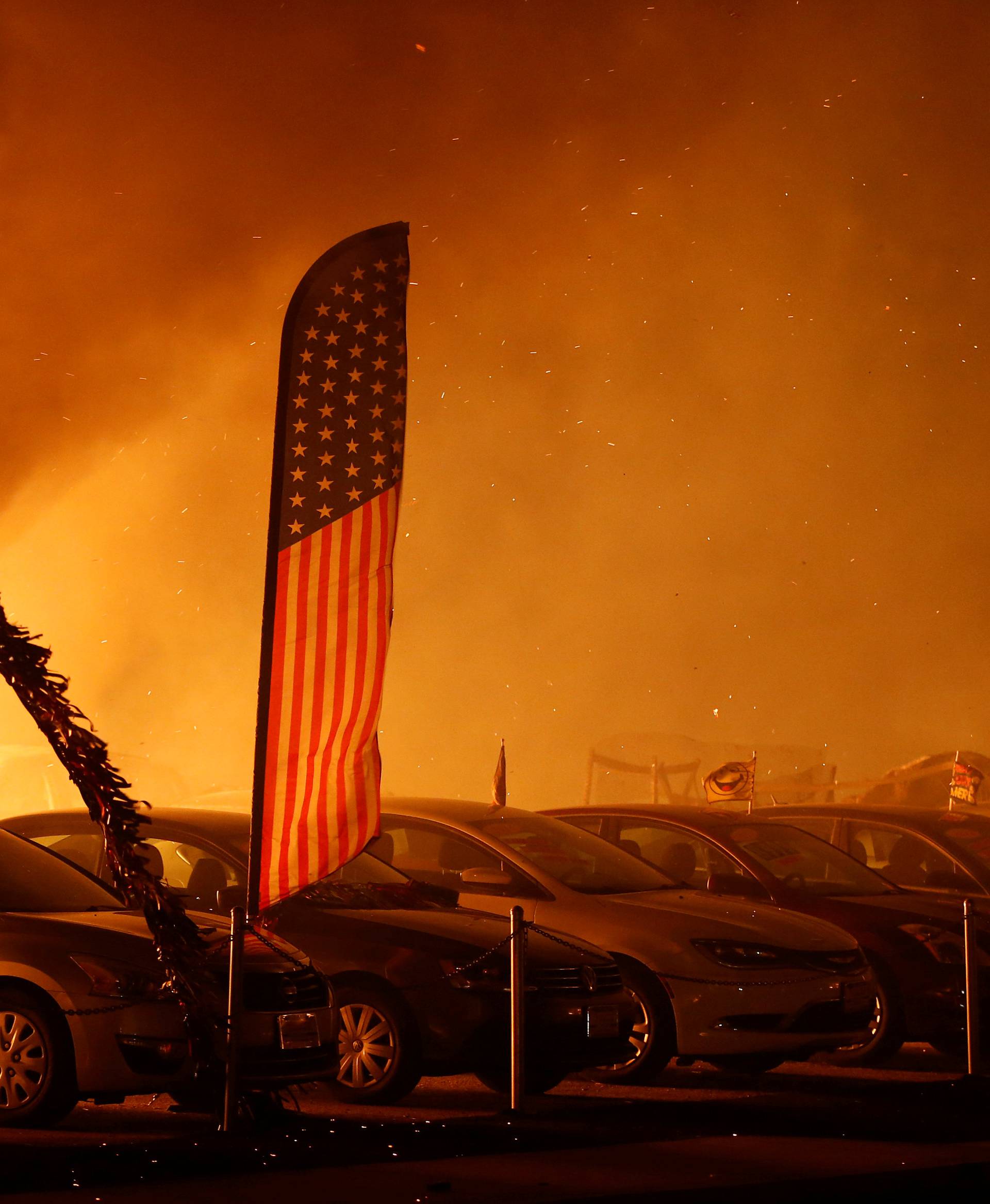 An American flag is seen at an engulfed car dealership during the Camp Fire in Paradise