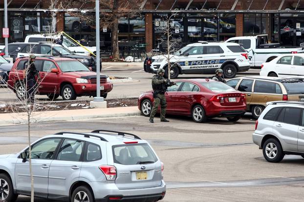 Law enforcement officers sweep the parking lot at the site of a shooting at a King Soopers grocery store in Boulder