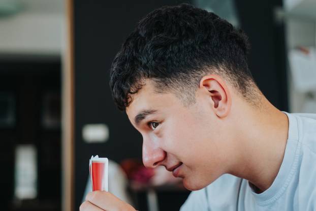 Young man having fun playing cards at home with a focused expression