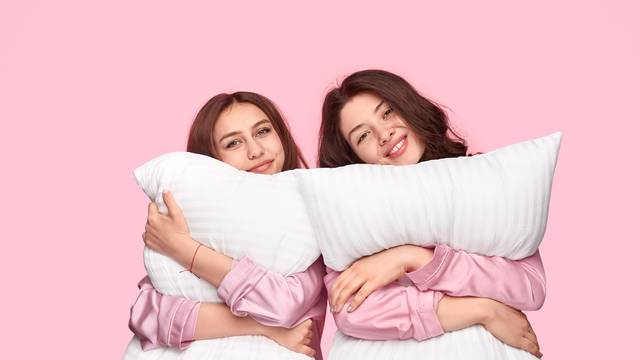 Young women hugging soft pillows during sleepover
