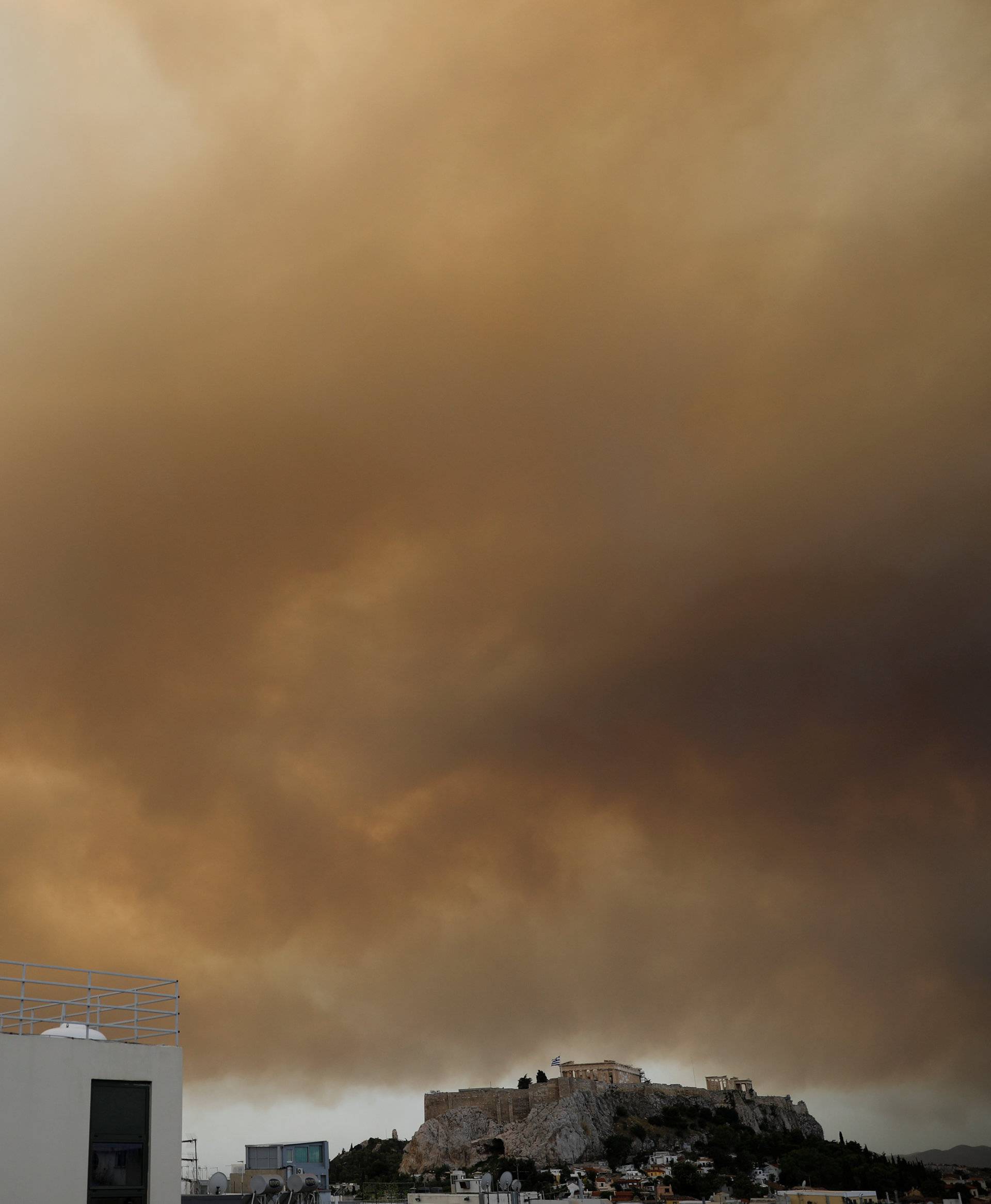 Smoke from a wildfire burning outside Athens is seen over the Parthenon temple atop the Acropolis hill in Athens