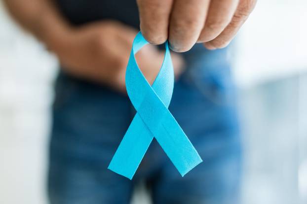 Senior man holding a blue cancer awareness ribbon