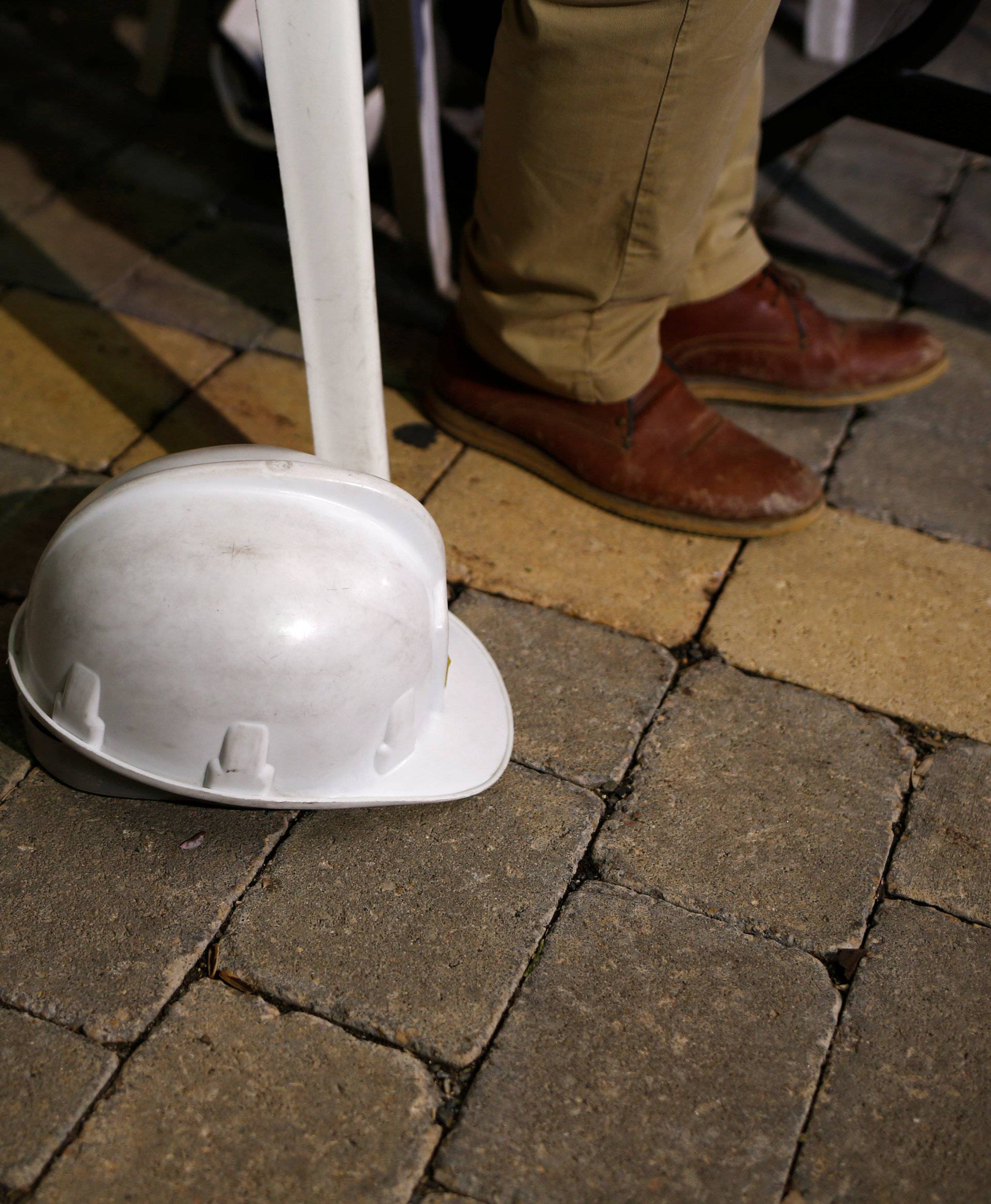 The construction helmet of a member of the team of engineers is seen on the ground as they give a news conference at the area where Julen fell into a deep in Totalan