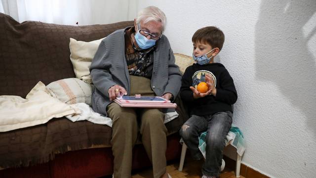 Florentina Martin, a 99 year-old woman who survived coronavirus disease (COVID-19), plays a digital puzzle with her great-grandson Pedro Valle at her home in Pinto