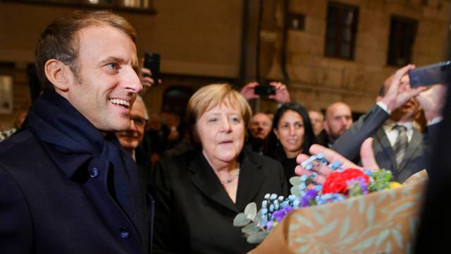 Outgoing German Chancellor Angela Merkel and France's President Emmanuel Macron receive flowers and a bottle of wine as gifts upon their arrival for talks, in Beaune