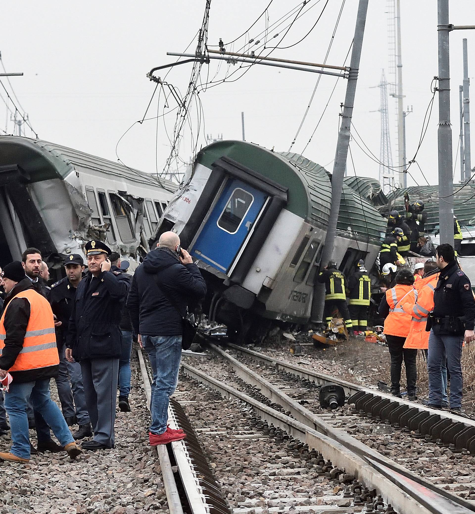 Rescue workers and police officers stand near derailed trains in Pioltello, on the outskirts of Milan