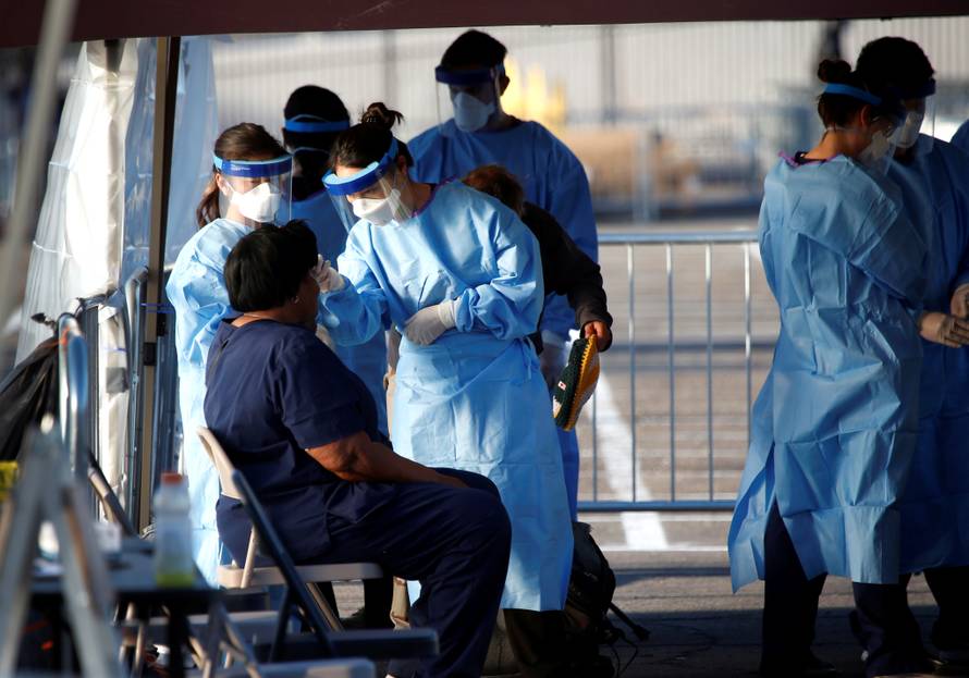 A medical student from Touro University Nevada takes the temperature of a person at a temporary parking lot with spaces marked for social distancing in Las Vegas