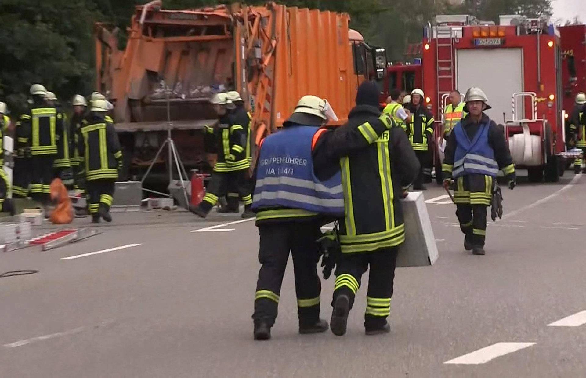 A still image taken from a video shows firefighters at a garbage truck which tipped over and landed on a car in Nagold