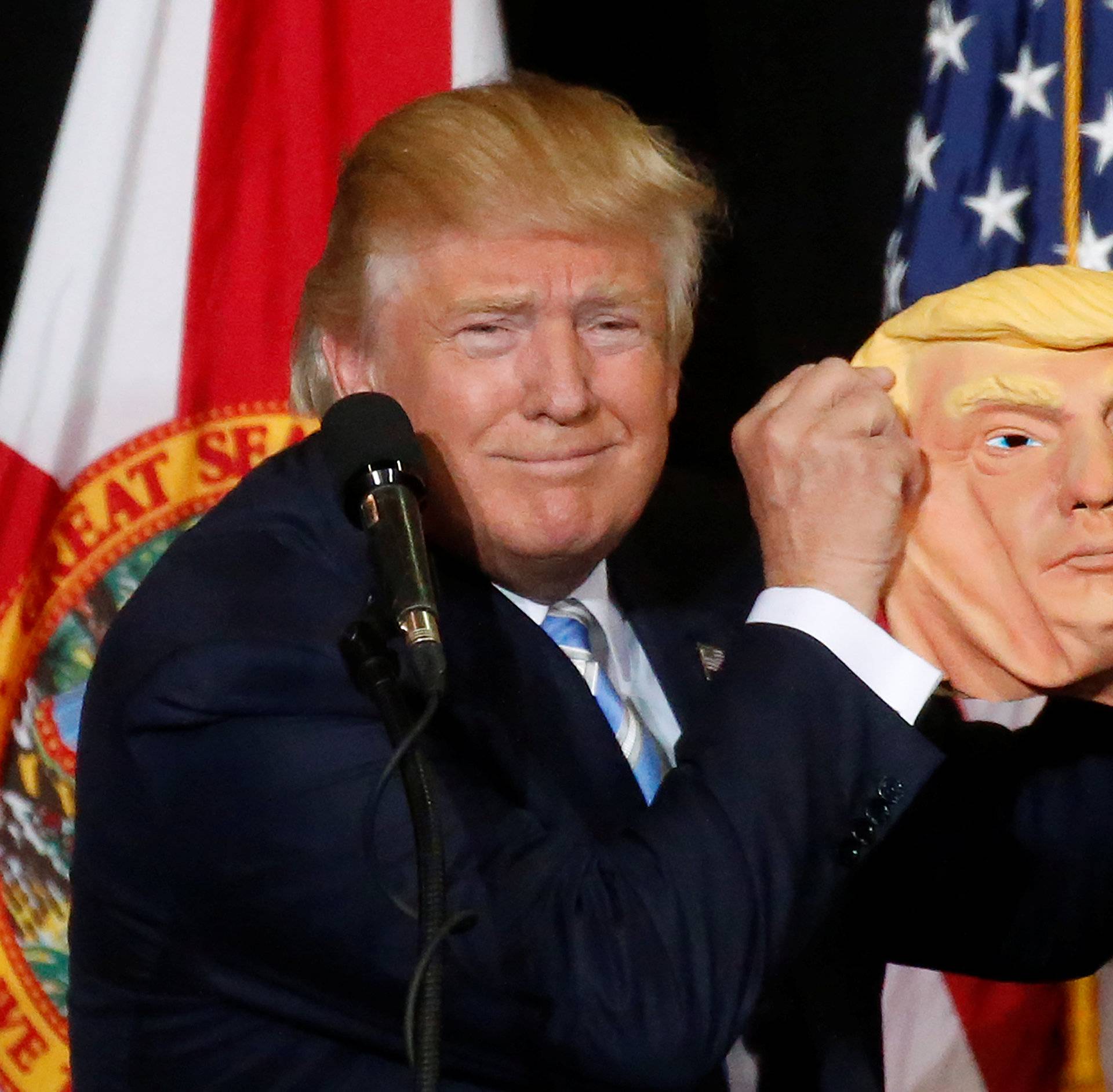 Republican presidential nominee Donald Trump holds up a mask of himself as he speaks during a campaign rally in Sarasota