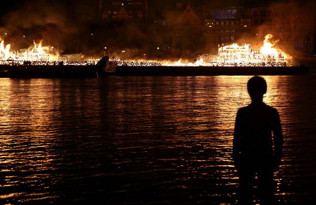 A boy watches as a 120-meter long model of the 17th century London skyline is set alight on the River Thames to commemorate the 1666 Great Fire of London in London