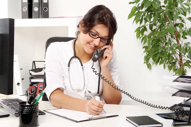 Young woman doctor talking by phone