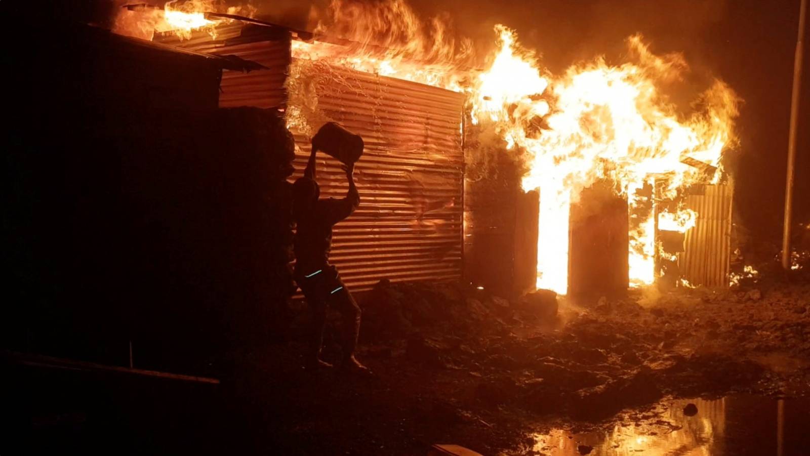 A person attempts to extinguish fire on a building after the volcanic eruption of Mount Nyiragongo, in Goma