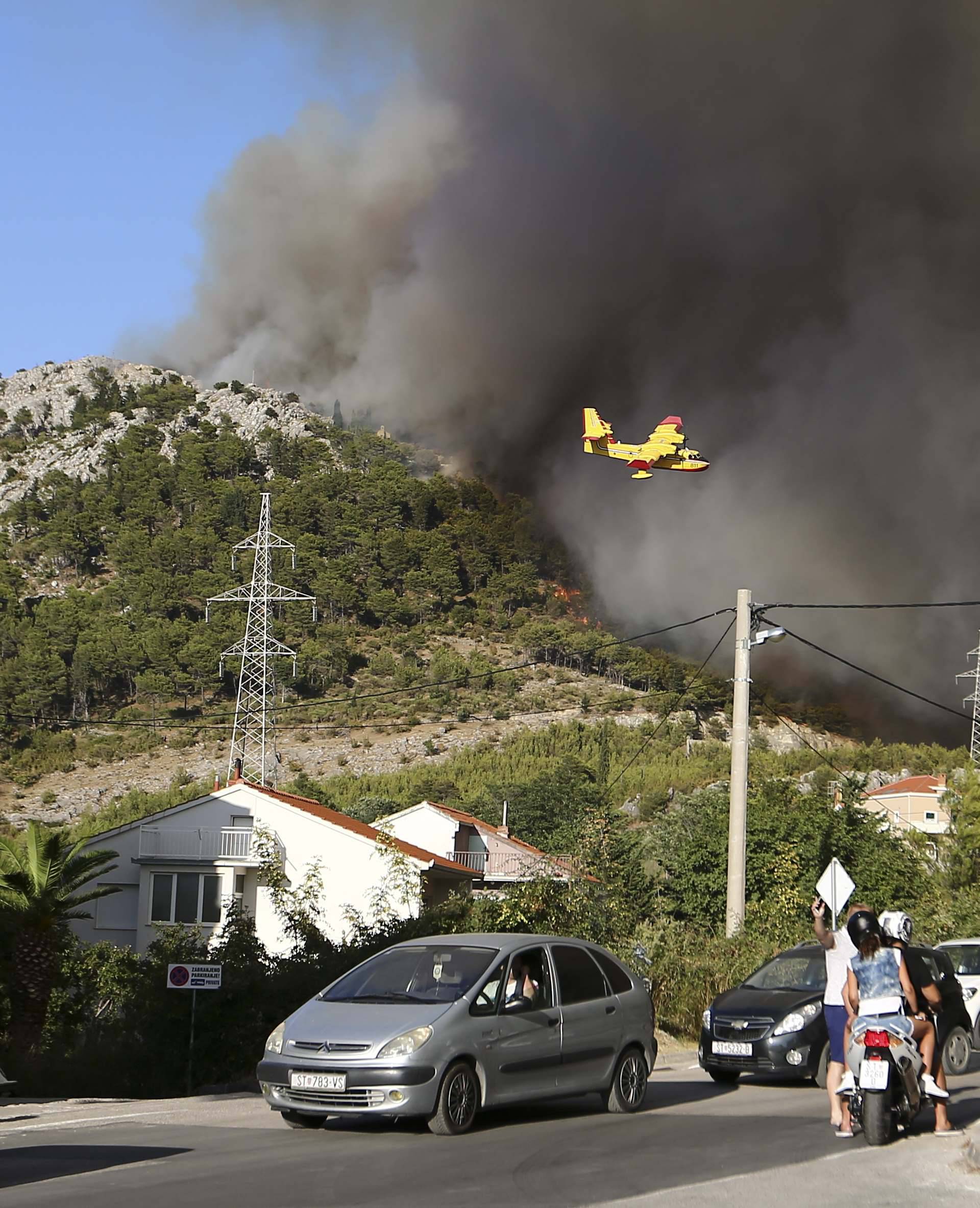Local residents watch a firefighting plane trying to extinguish a wildfire in the village of Mravinc near Split