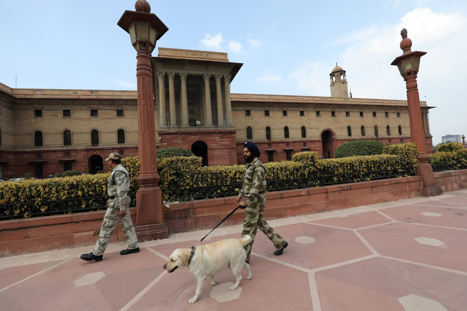 Members of Central Industrial Security Force patrol with a sniffer dog outside India's Home Ministry building in New Delhi