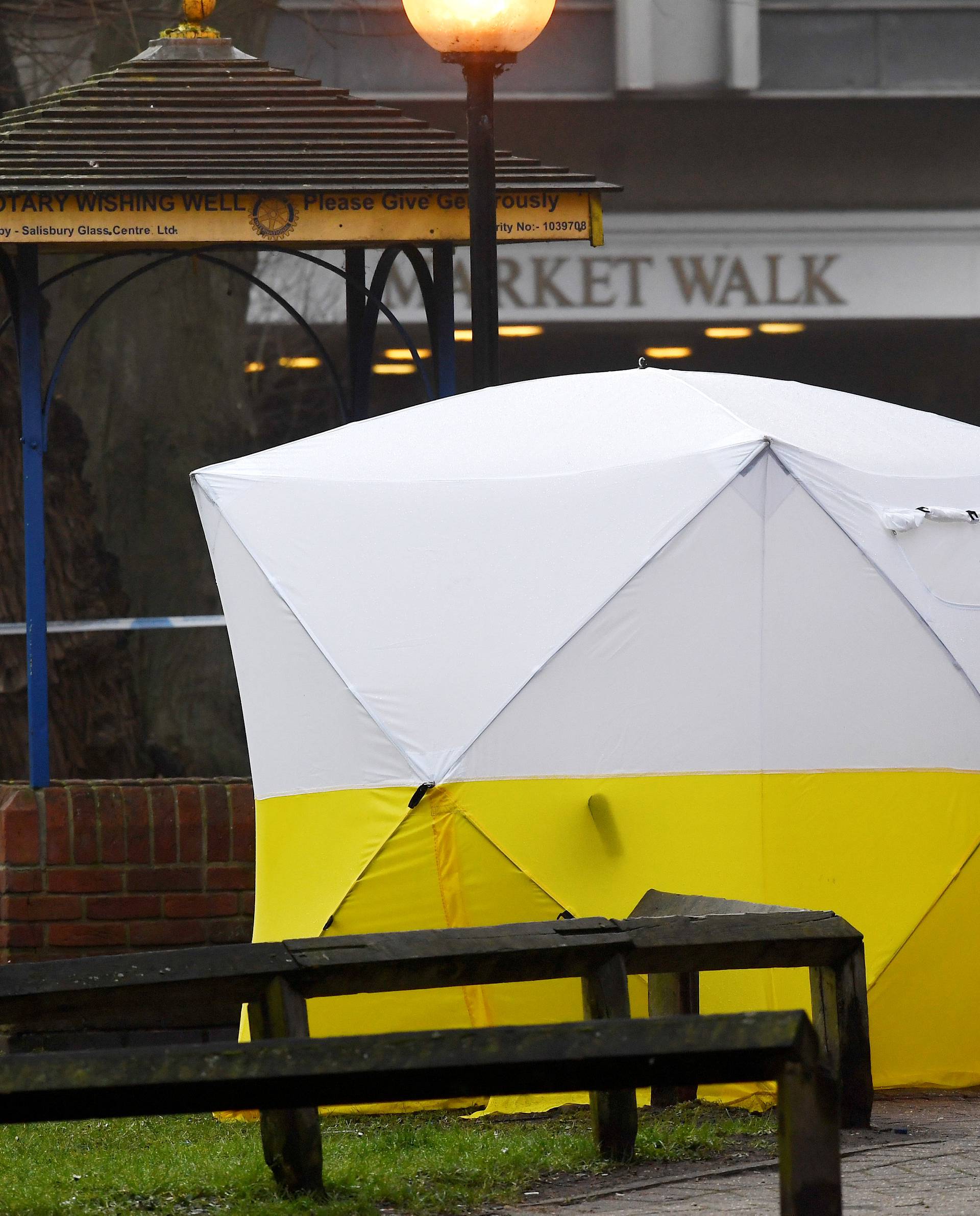 Police officers stand at crime scene tape, as a tent covers a park bench on which former Russian inteligence officer Sergei Skripal, and a woman were found unconscious after they had been exposed to an unknown substance, in Salisbury