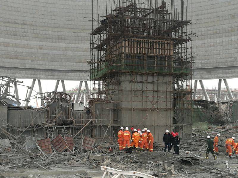 Rescue workers search the site where a power plant's cooling tower under construction collapsed, in Fengcheng