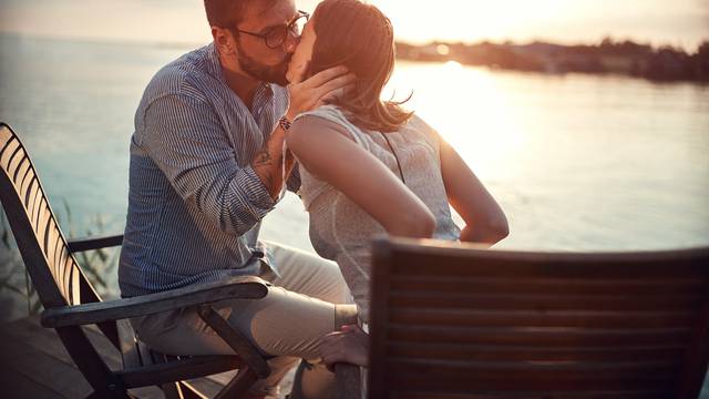 beardy caucasian young guy kissing his woman by the sea