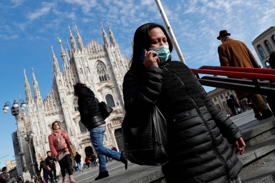 A woman wearing a protective face mask to prevent contracting the coronavirus enters a subway station in Milan