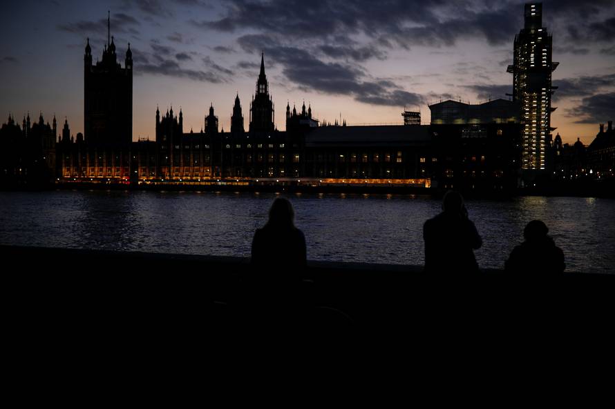 People enjoy the view on the south bank of the River Thames, opposite the Houses of Parliament, in Westminster, central London