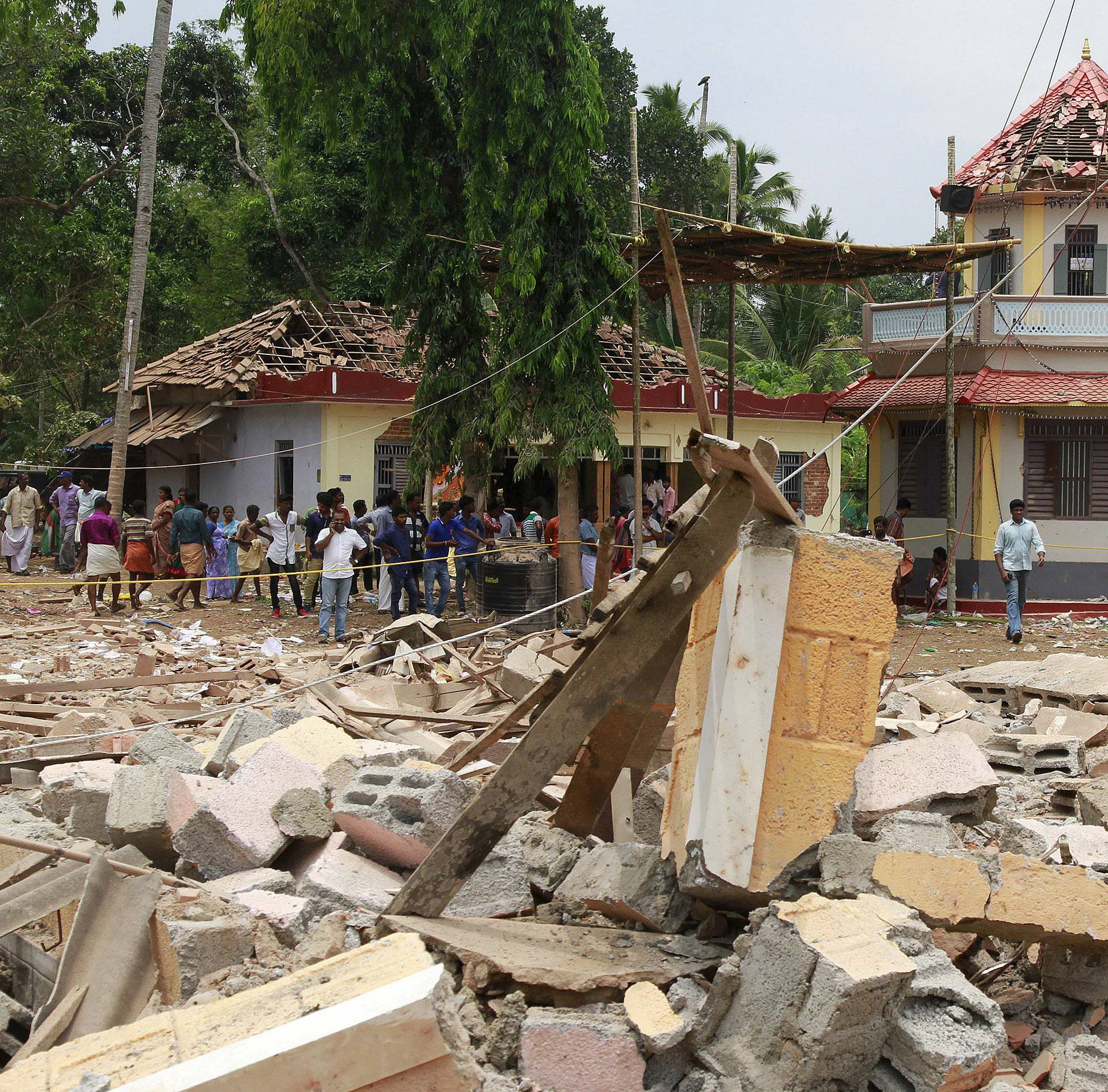 People stand next to debris after a broke out at a temple in Kollam in the southern state of Kerala