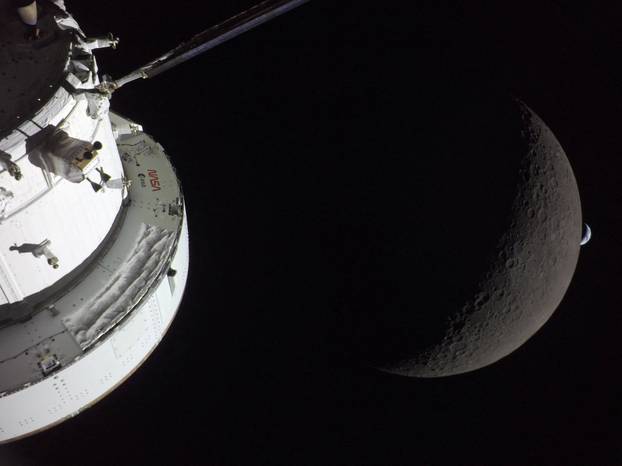 NASA’s Orion spacecraft is seen in the foreground, lit up by the Sun as a first quarter Moon is visible behind it