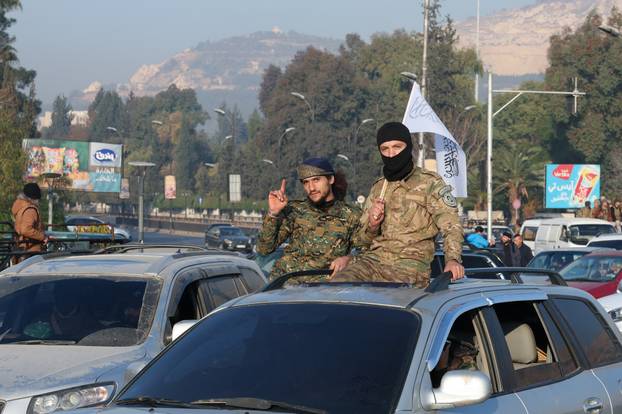 Rebel fighters ride on a car, in Damascus