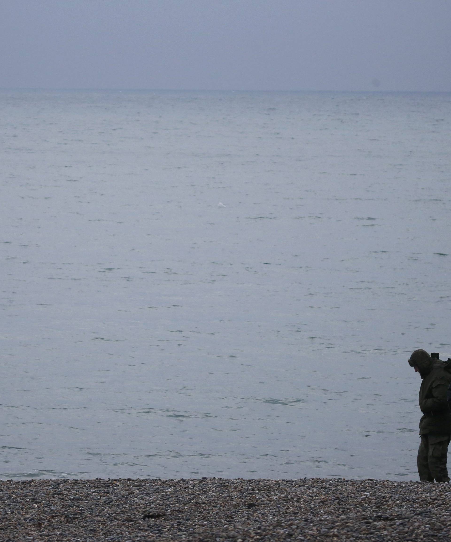 Russian servicemen stand at shores of Black Sea as boat of Russian Emergencies Ministry sails near crash site of Russian military Tu-154 plane, in Sochi suburb of Khosta