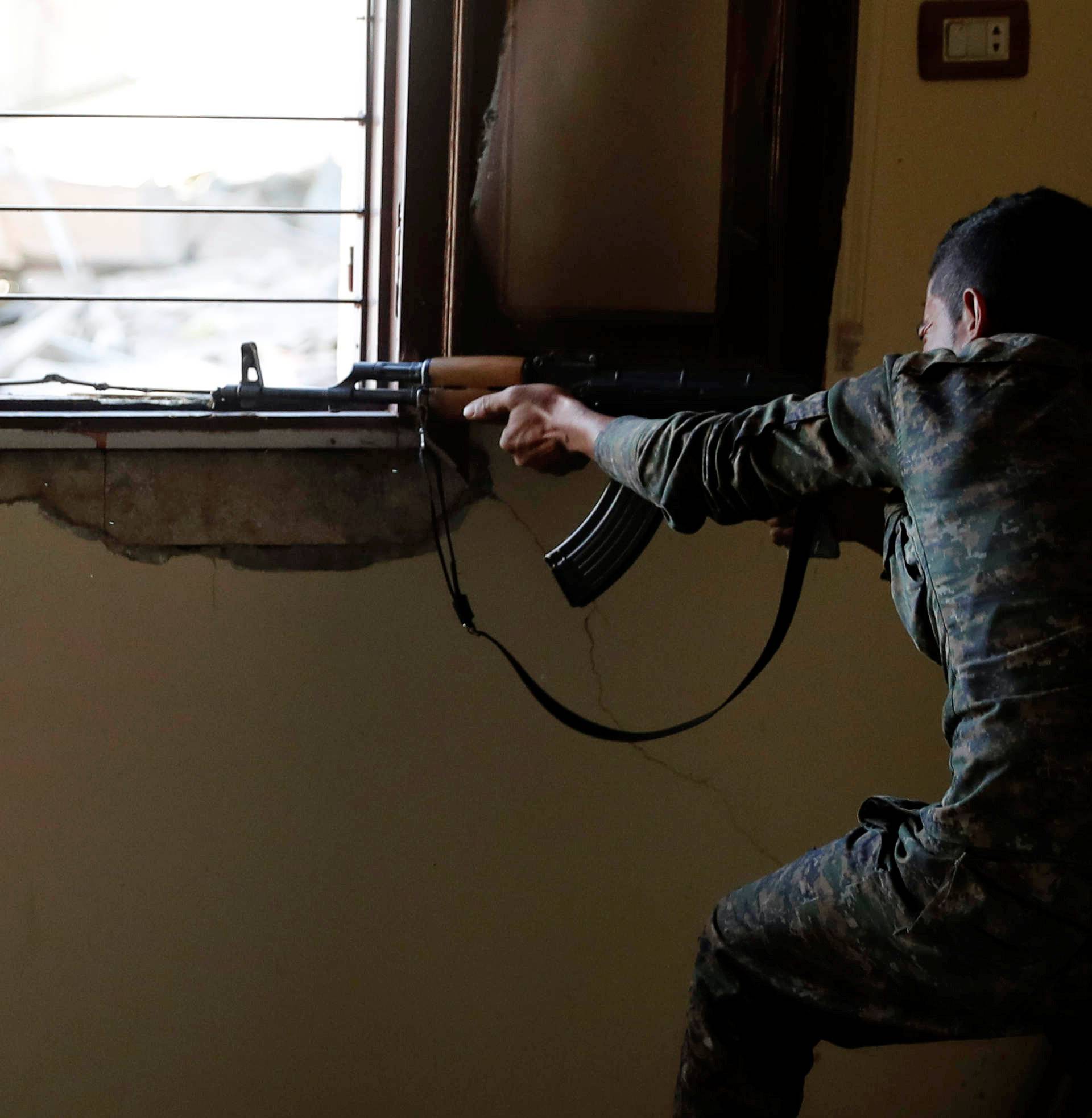 A bullet casing flies near the head of a fighter of Syrian Democratic Forces as he fires his weapon towards the Islamic State militants, at the frontline in Raqqa