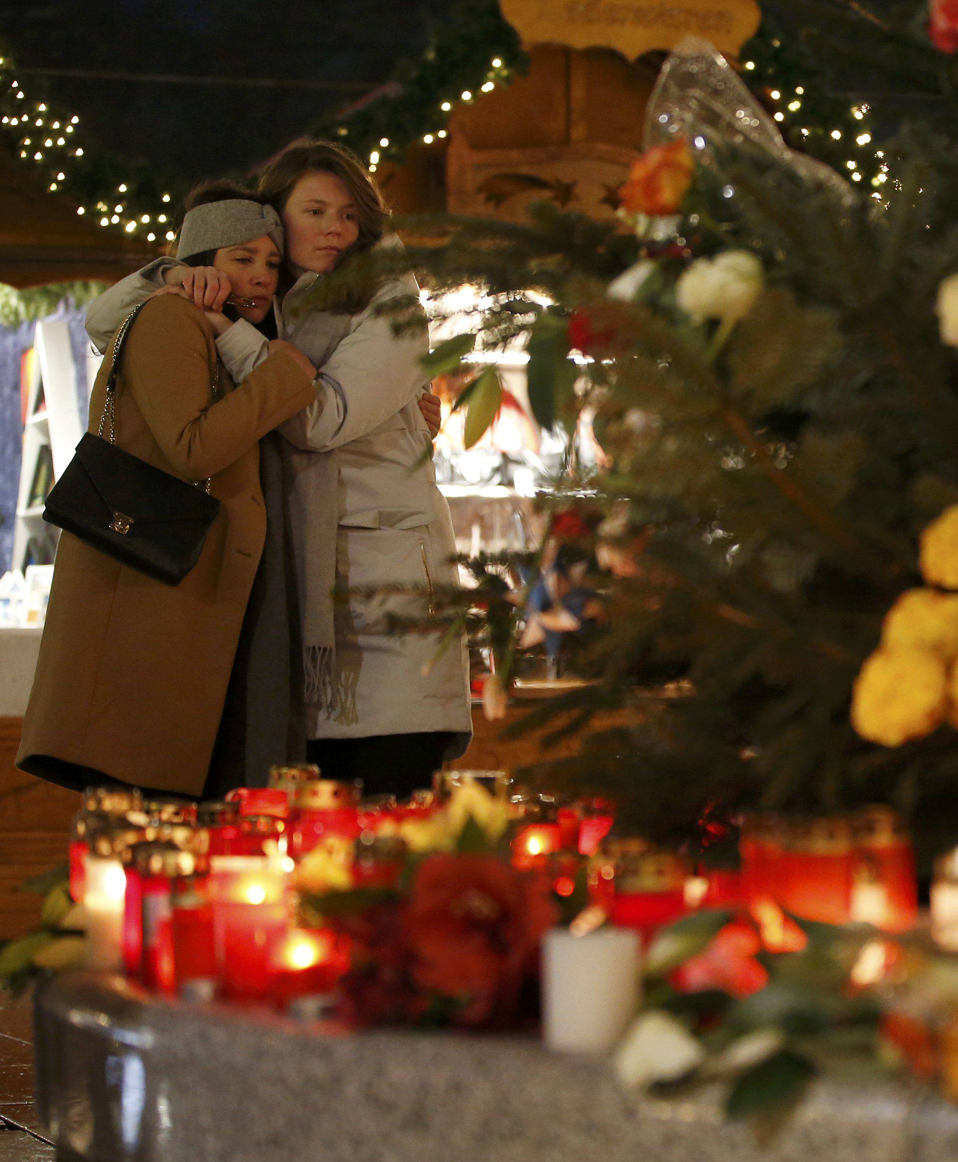 People mourn beside flowers and candles placed at the Christmas market at Breitscheid square in Berlin