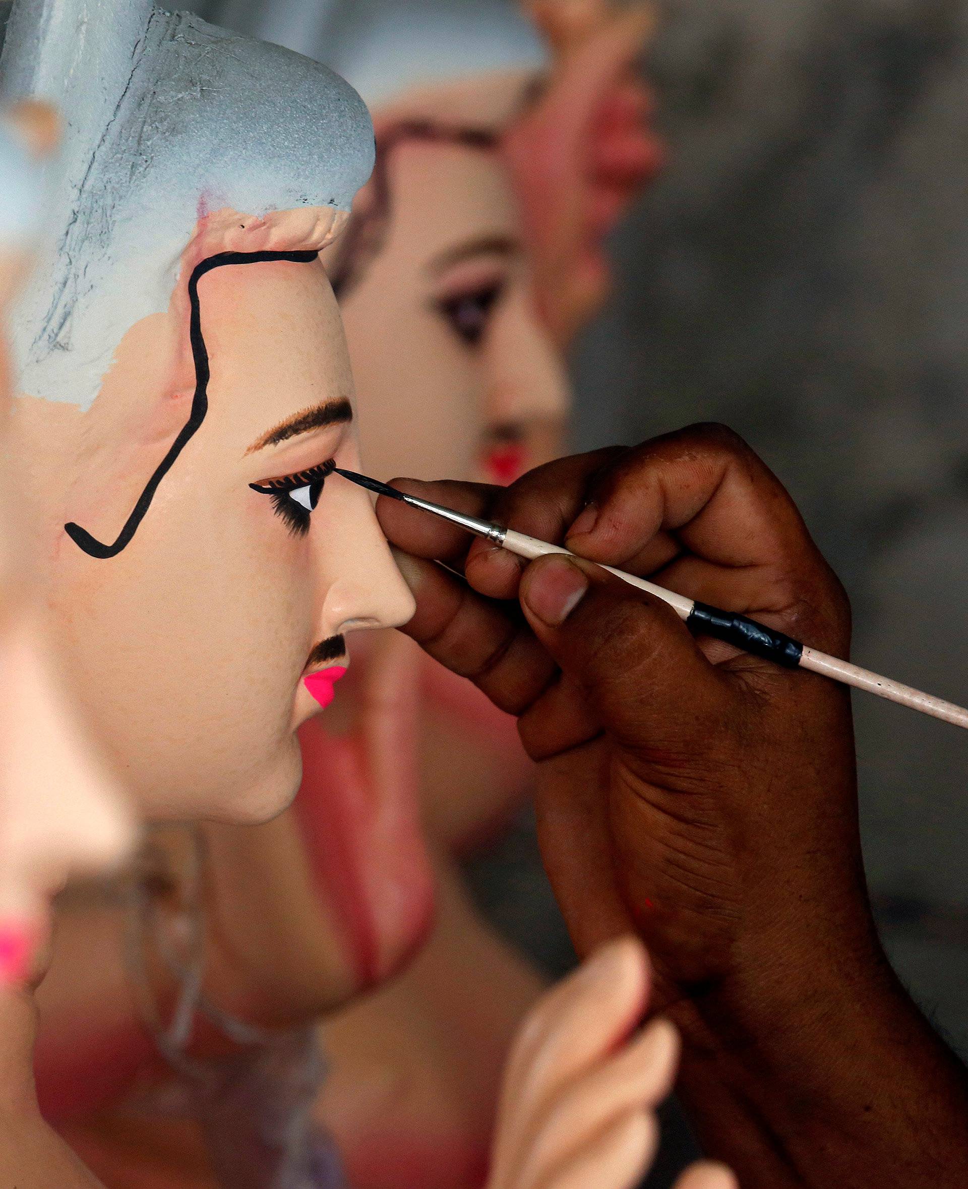 An artisan paints an idol of Lord Vishwakarma, the Hindu deity of architecture and machinery, inside a workshop ahead of the Vishwakarma festival in Kolkata