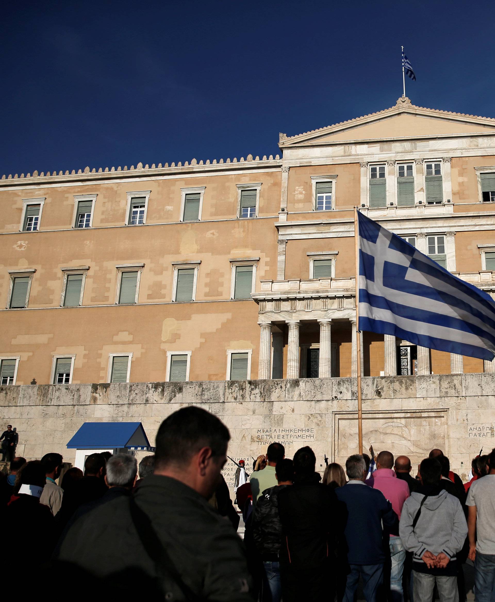 A protester waves a Greek flag during a demonstration outside the parliament building in central Athens