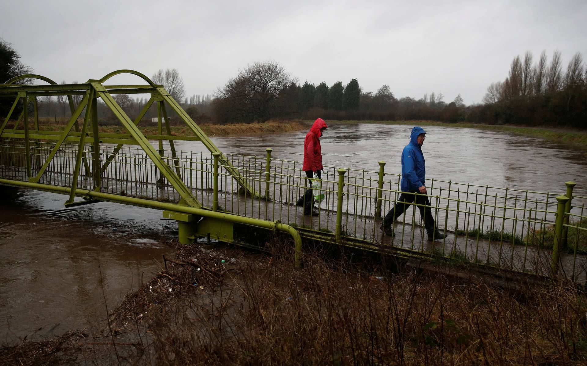 People walk across a footbridge over a heavily flooded River Mersey as Storm Christoph arrives in Manchester