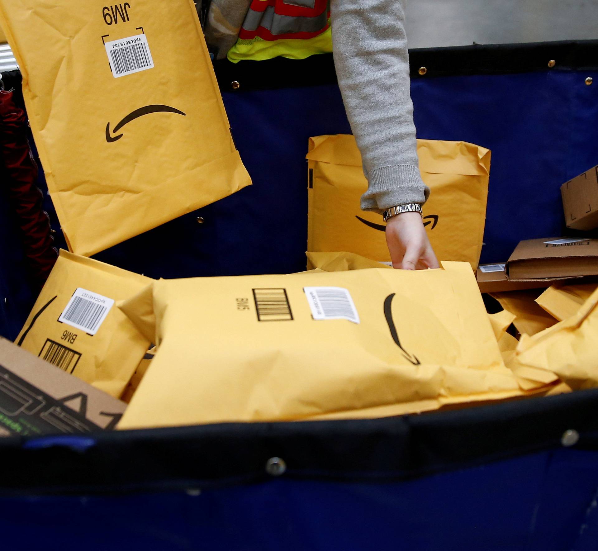 FILE PHOTO: Area manager Wells retrieves packages to put them on a conveyor line for scanning and labeling at the Amazon fulfillment center in Kent