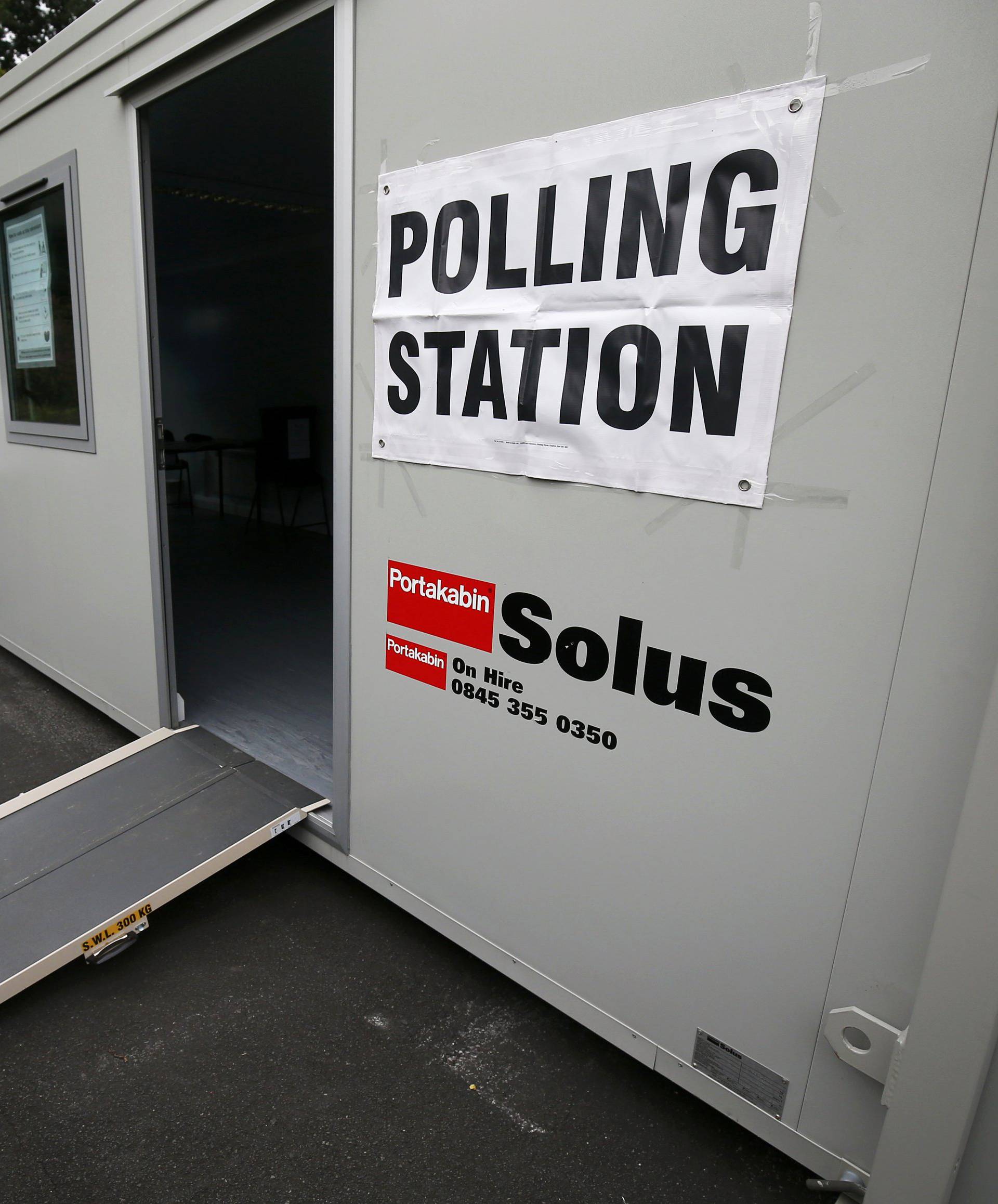 A man puts up a sign at a polling station for the Referendum on the European Union in Heald Green, Stockport, Britain