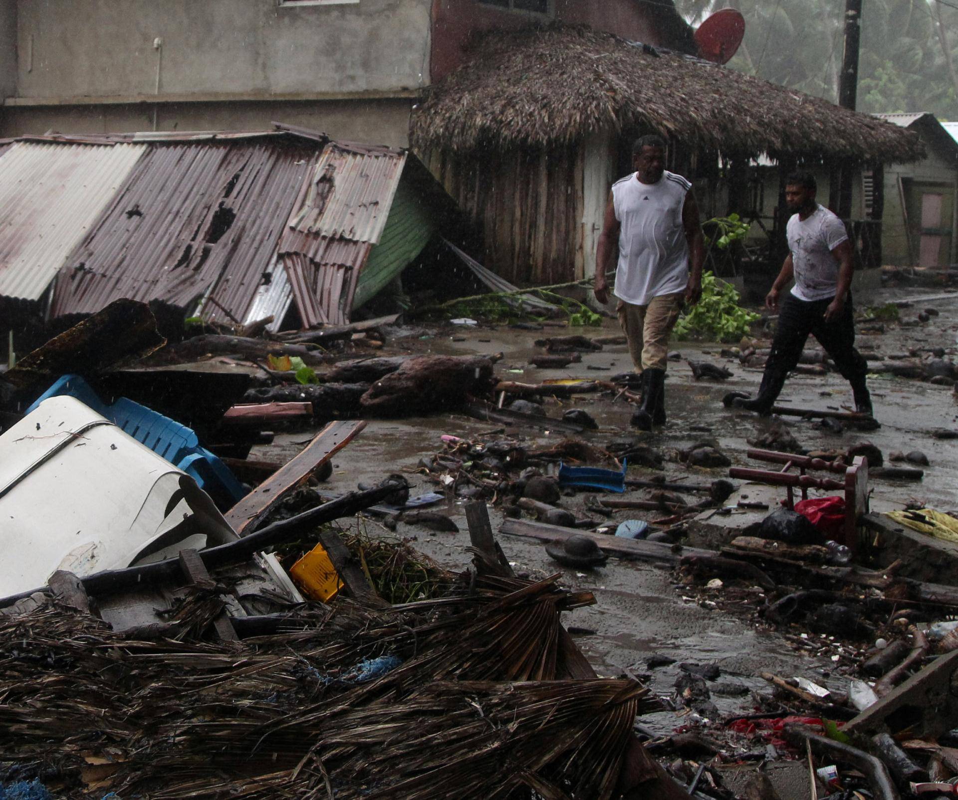 People walk past debris as Hurricane Irma moves off from the northern coast of the Dominican Republic, in Nagua