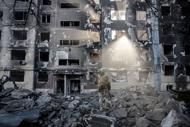 Ukrainian serviceman stands near an apartment building damaged by a Russian military strike in the frontline town of Kostiantynivka