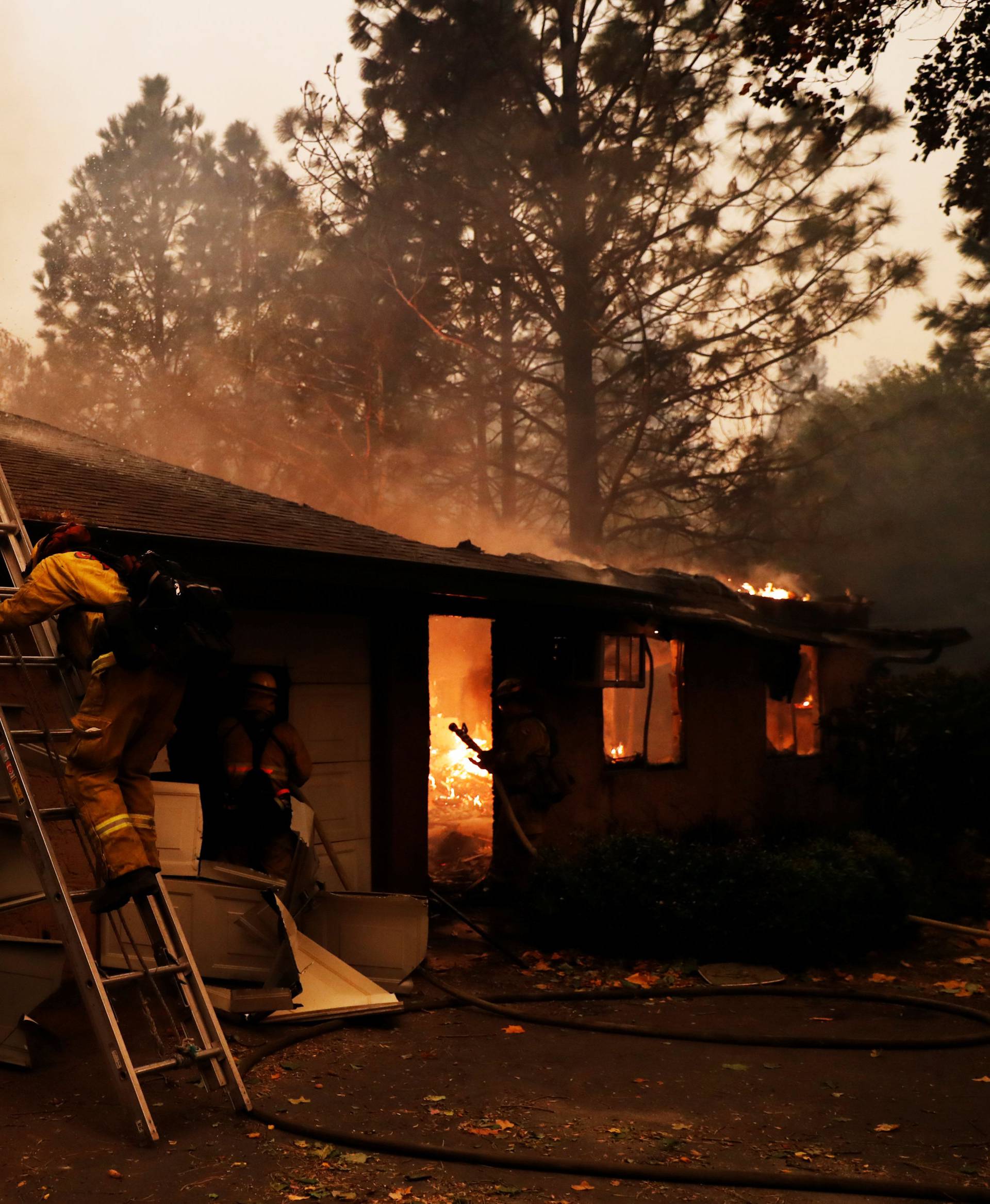 Firefighters battle to save homes after mandatory evacuations were ordered at the Camp Fire in Paradise