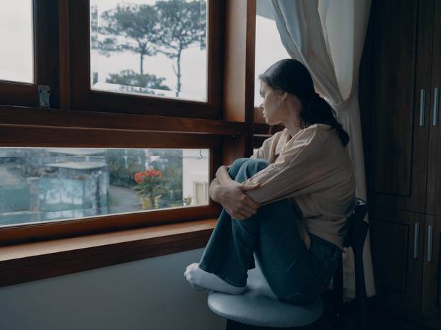 Woman fall depression sitting by the window and looking at nature, rainy weather and discouragement, home life style, loneliness.