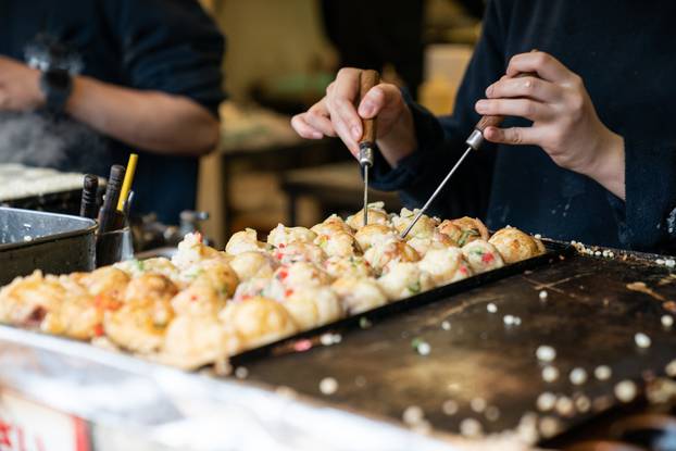 Closeup,Cropped,Shot,Hands,Of,Chef,Using,Two,Takoyaki,Picks