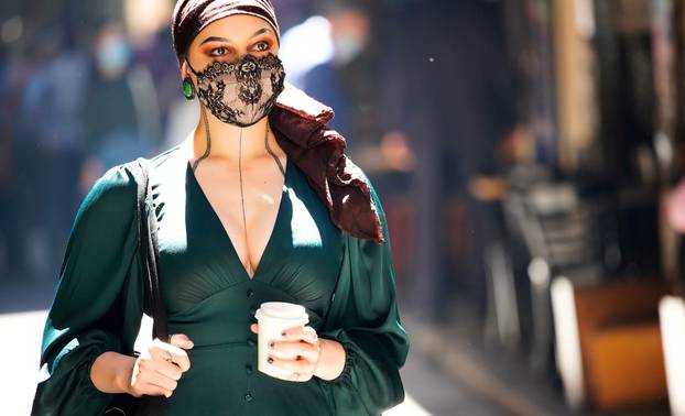 FILE PHOTO: A woman wearing a face masks walks past cafes after coronavirus disease restrictions were eased in Melbourne