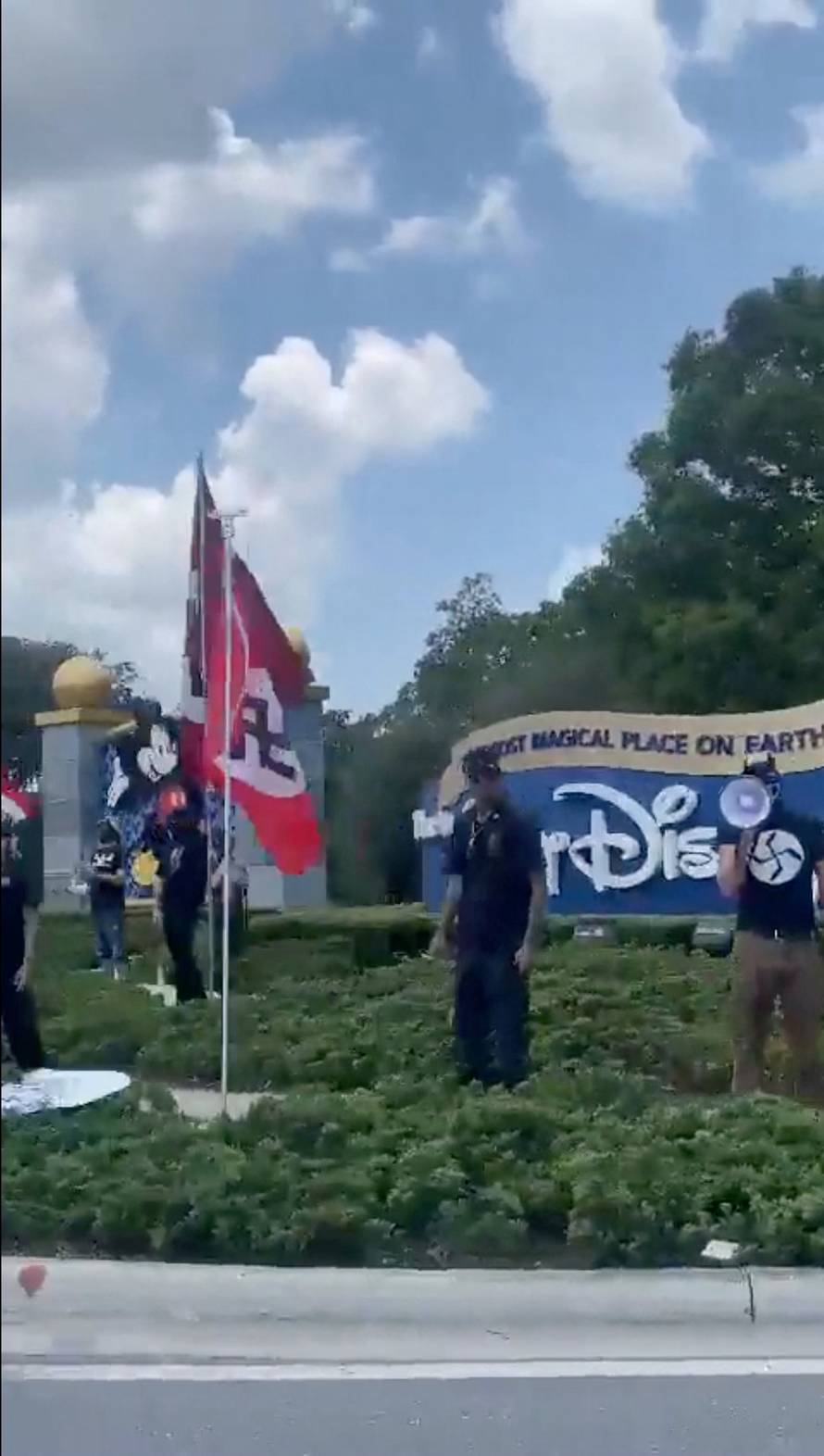 People displaying Nazi flags and symbols protest outside the entrance to Walt Disney World Resort in Orlando, FL