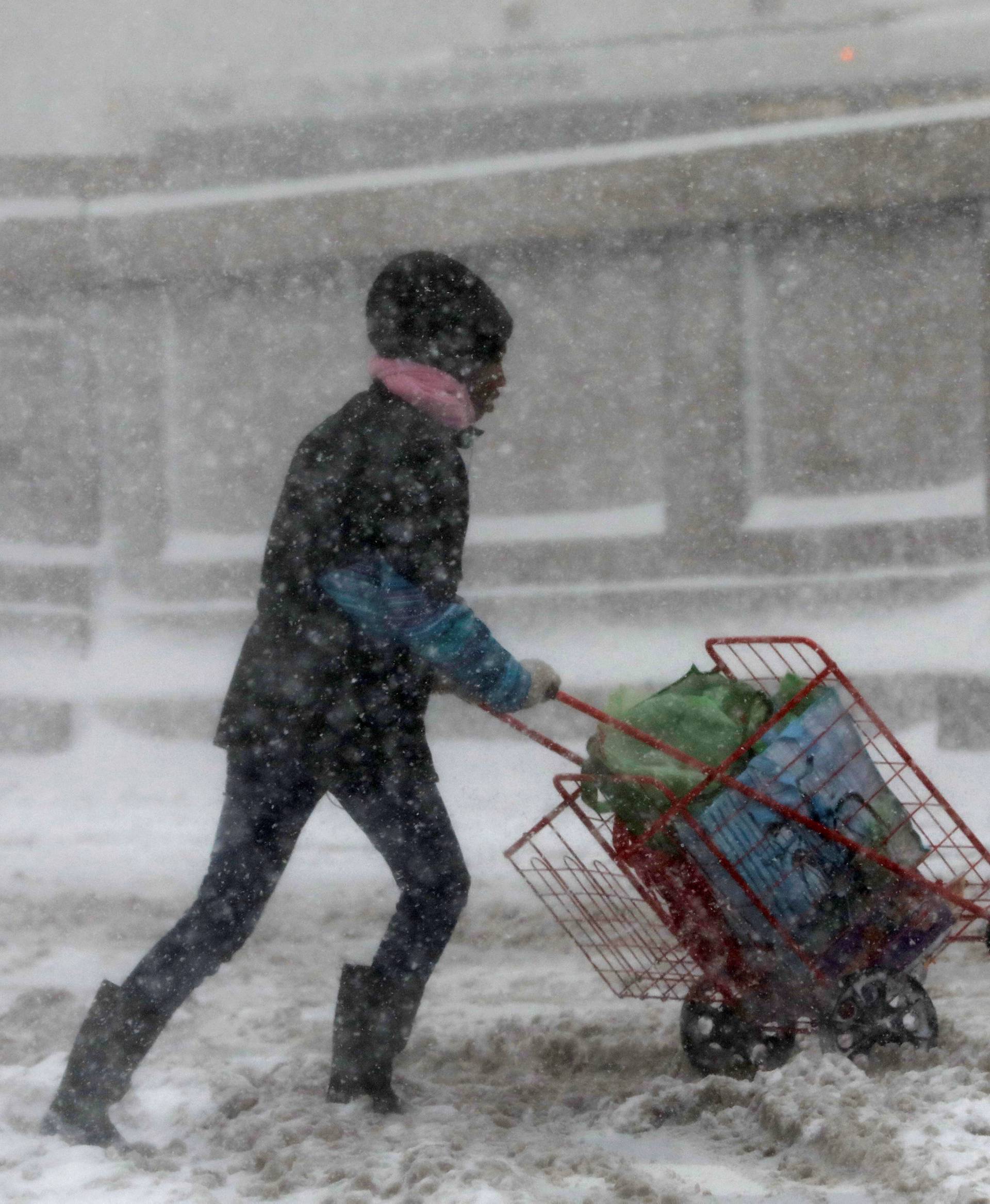 A woman struggles against wind and snow in upper Manhattan during a snowstorm in New York City